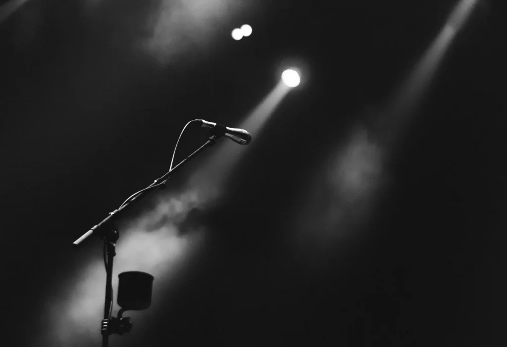 Image of microphone stand on dark stage illuminated by spotlight for the BNI Synergy Member Spotlight Series